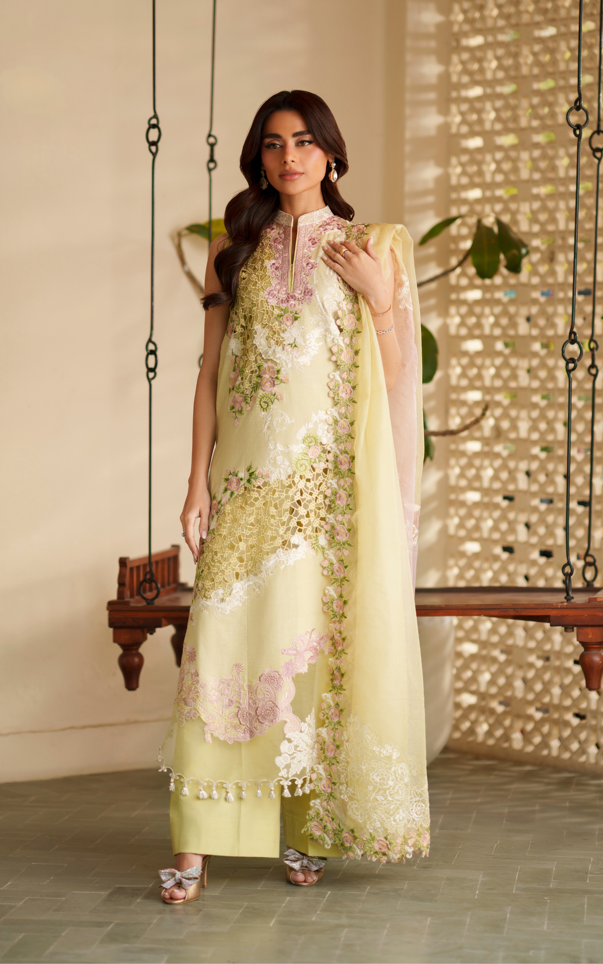 Woman wearing a light green embroidered outfit with a matching dupatta in a decorated indoor setting.